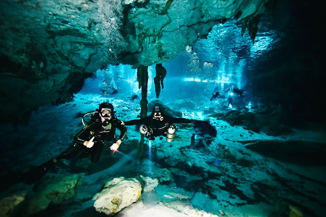 Scuba divers exploring the underwater cavern and stalactites at Cenote Dos Ojos