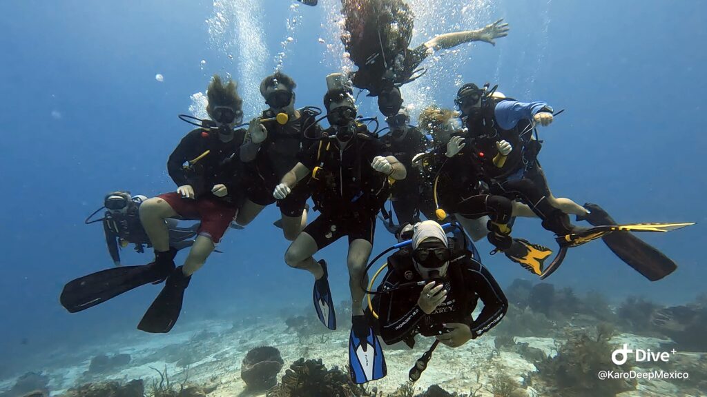 Group of scuba divers underwater on a reef during the best time to dive in Playa del Carmen with Deep México